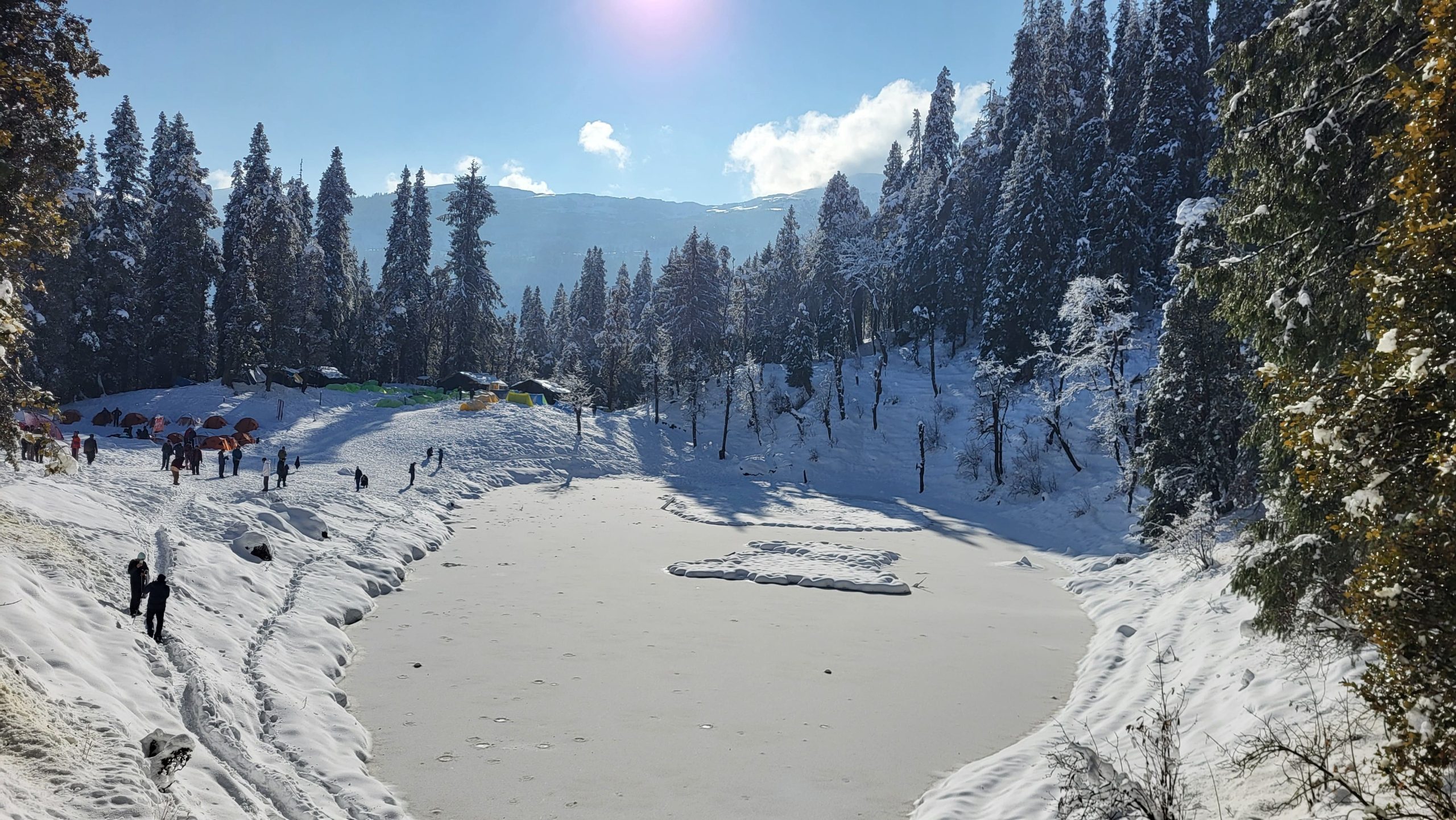 Juda ka talab frozen lake surrounded by snow-covered pine trees